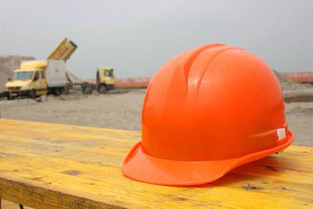 Constuction hat on work bench with trucks in background