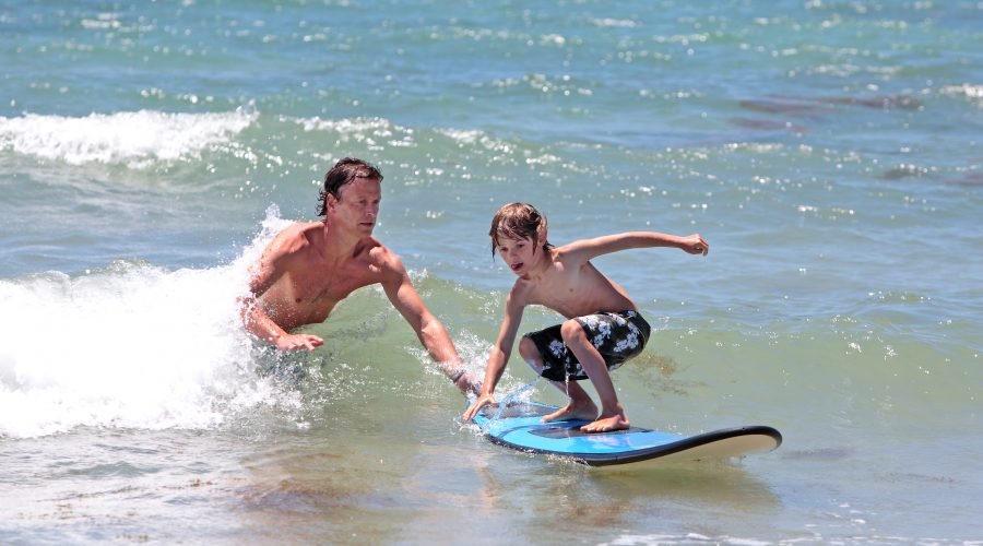 father teaching son to surf