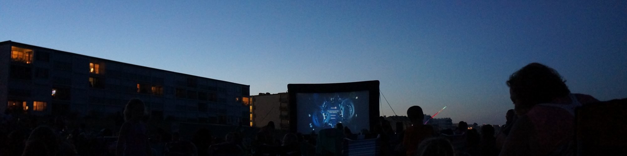 movie screen on the beach with people watching