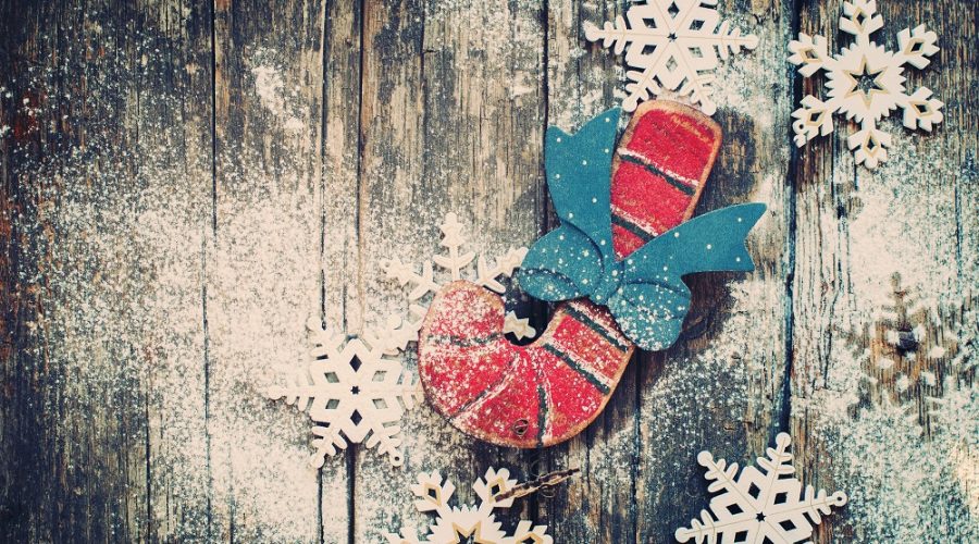 a handmade wooden candy cane and snowflakes on distressed wood background