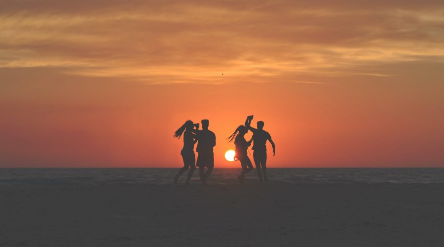 four people dancing on the beach