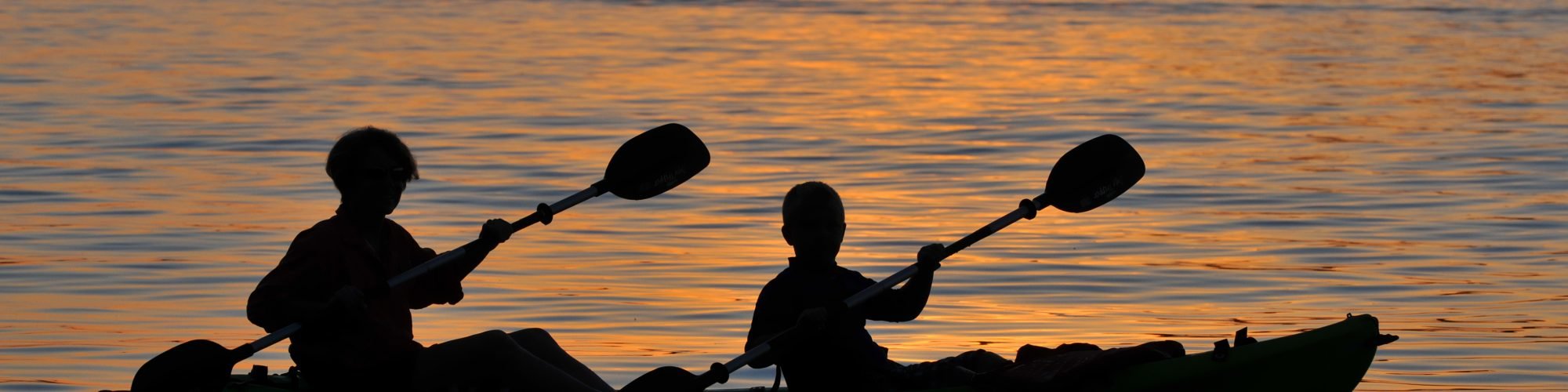 two people kayaking at sunset