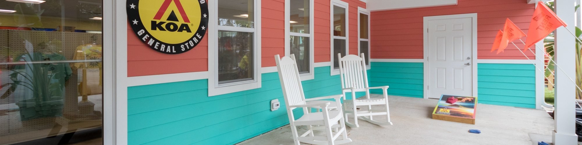 Chincoteague Island KOA General Store with bag toss game in front of bright coral and teal building