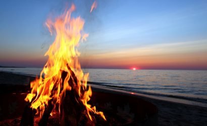 bonfire on the beach with the ocean and sunset in the background