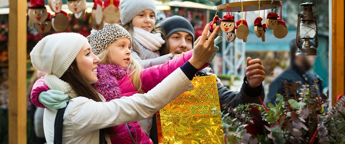 family of four admiring holiday ornaments at outside market