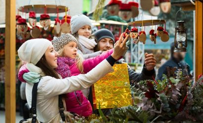 family of four admiring holiday ornaments at outside market