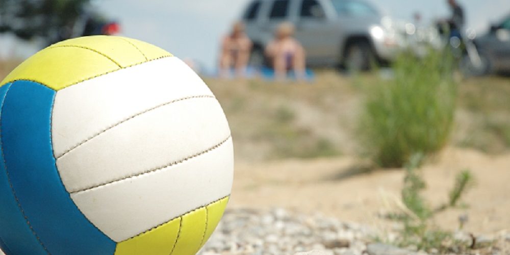 red white blue volleyball outside on a bed of gravel