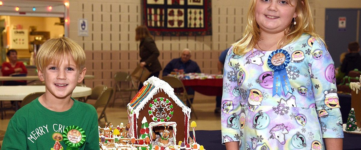girl and boy standing next to the winning gingerbread house