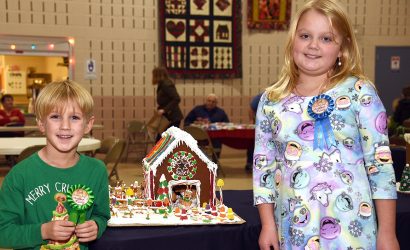 girl and boy standing next to the winning gingerbread house
