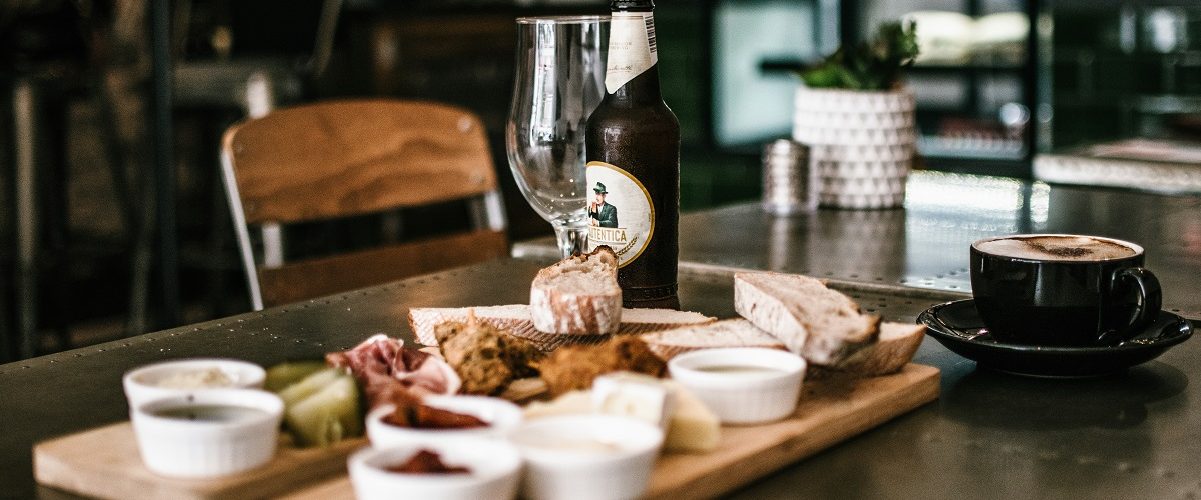 restaurant table set with cheese board and bottled beer
